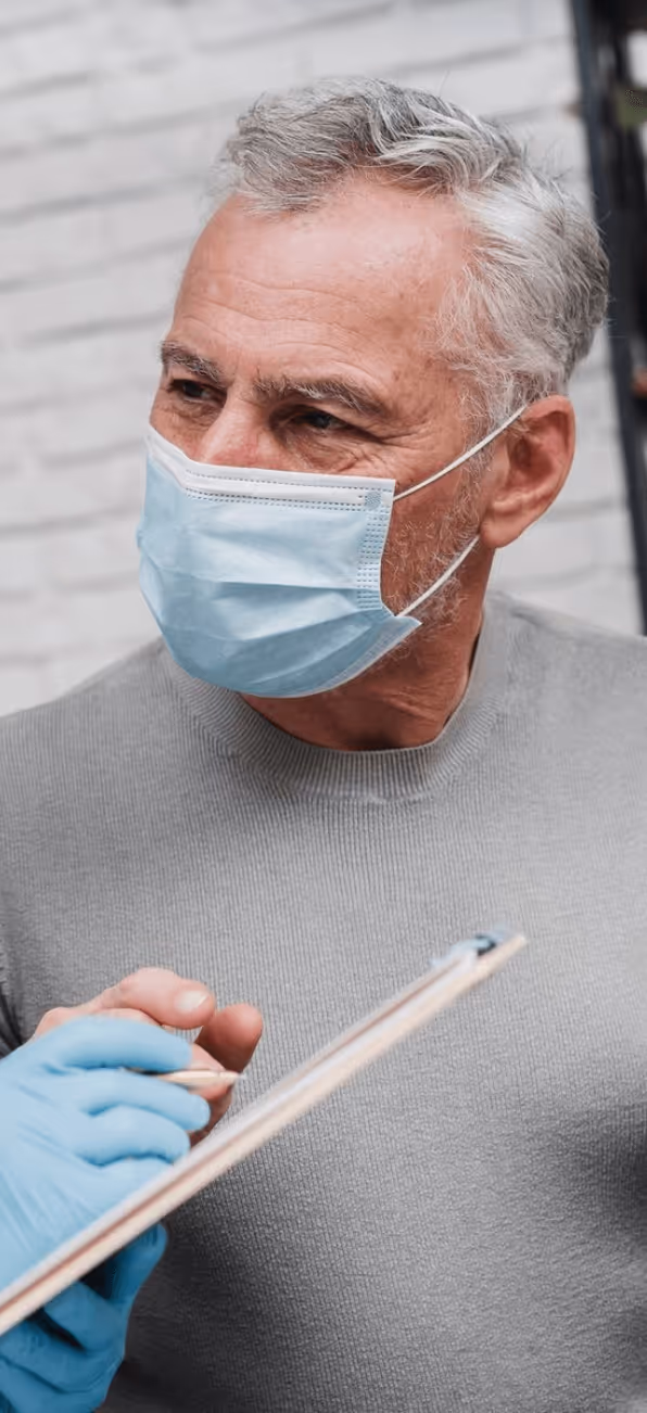 A man wearing a mask talks to a health worker